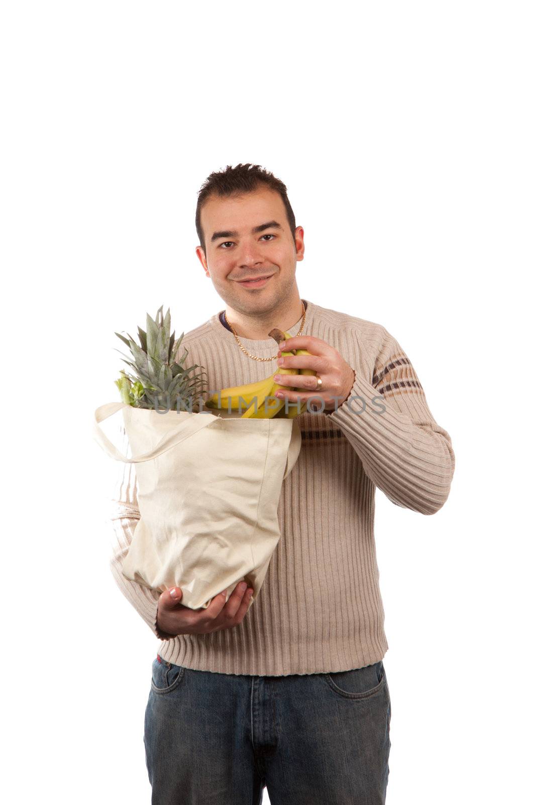 White male grocery shopper smiling while holding a canvas bag full of fresh food items.