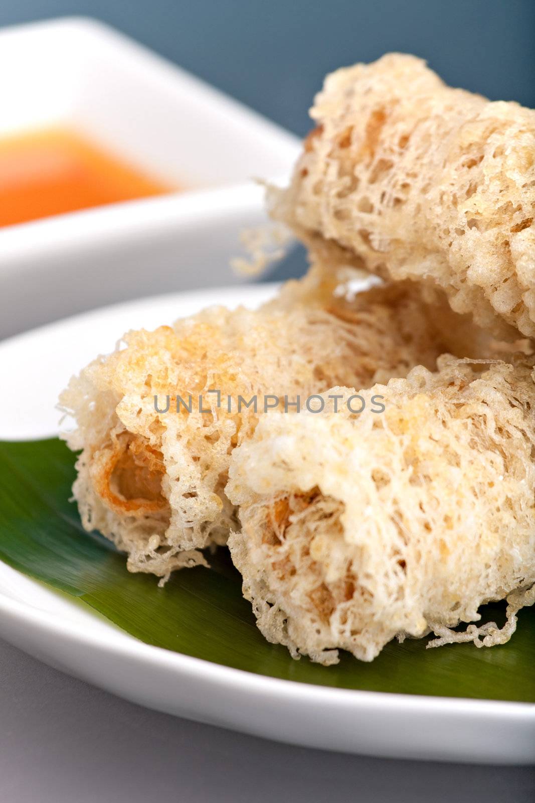 Plate of crispy taro root crusted Thai spring rolls appetizer with sweet and savory dipping sauce.