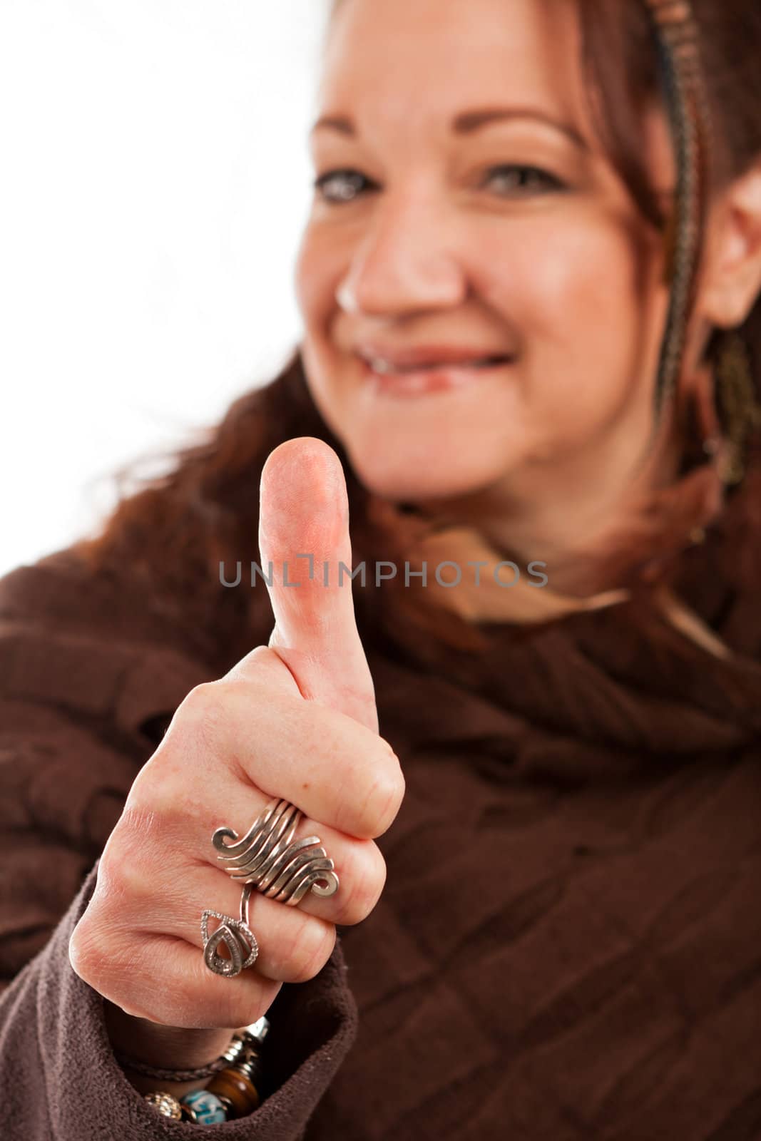 Middle aged woman smiling and holding her thumb up in approval.  Shallow depth of field.