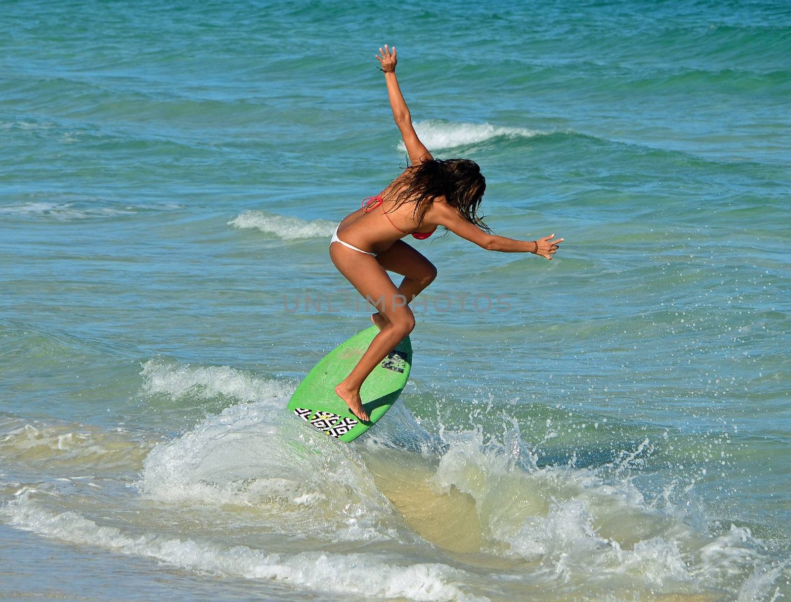 sensuous young woman surfer skim boarding in the surf on miami beach