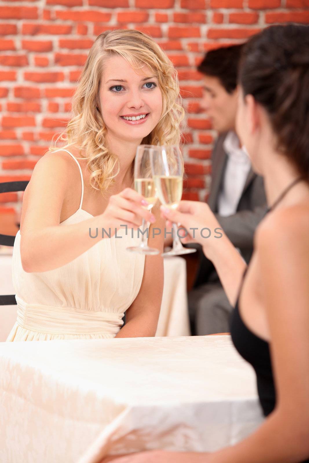 Girls drinking champagne in a restaurant by phovoir