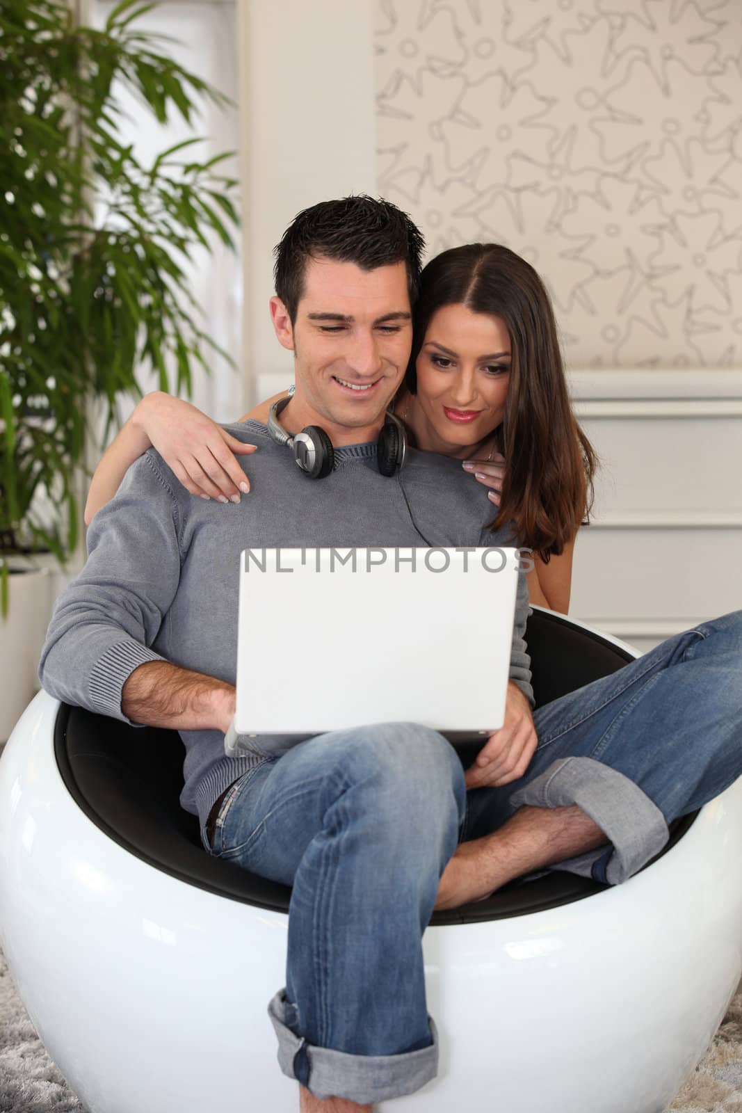 Young casual couple looking at a laptop by phovoir