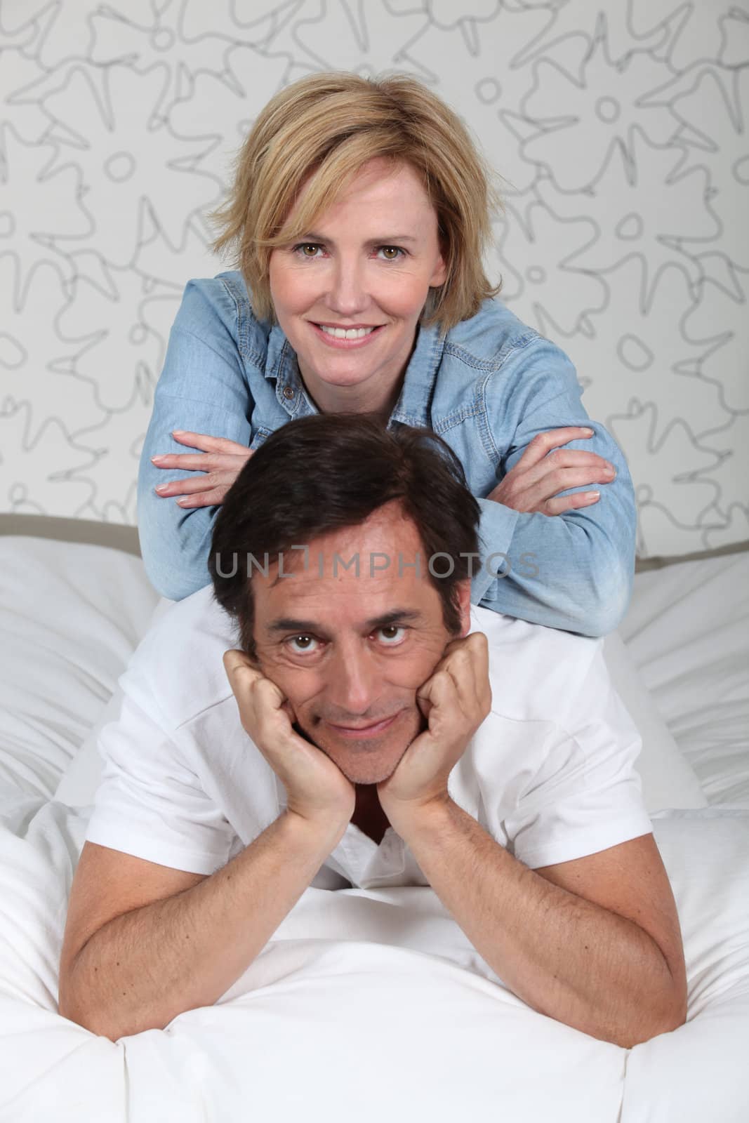 Married couple relaxing on bed by phovoir