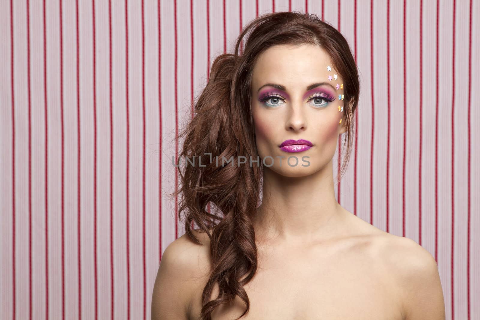 Young woman with colorful makeup and star candy glued to her face
