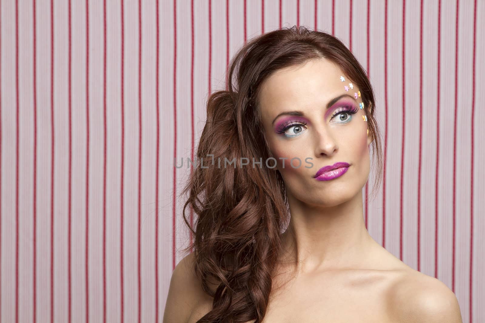 Young woman with colorful makeup and star candy glued to her face
