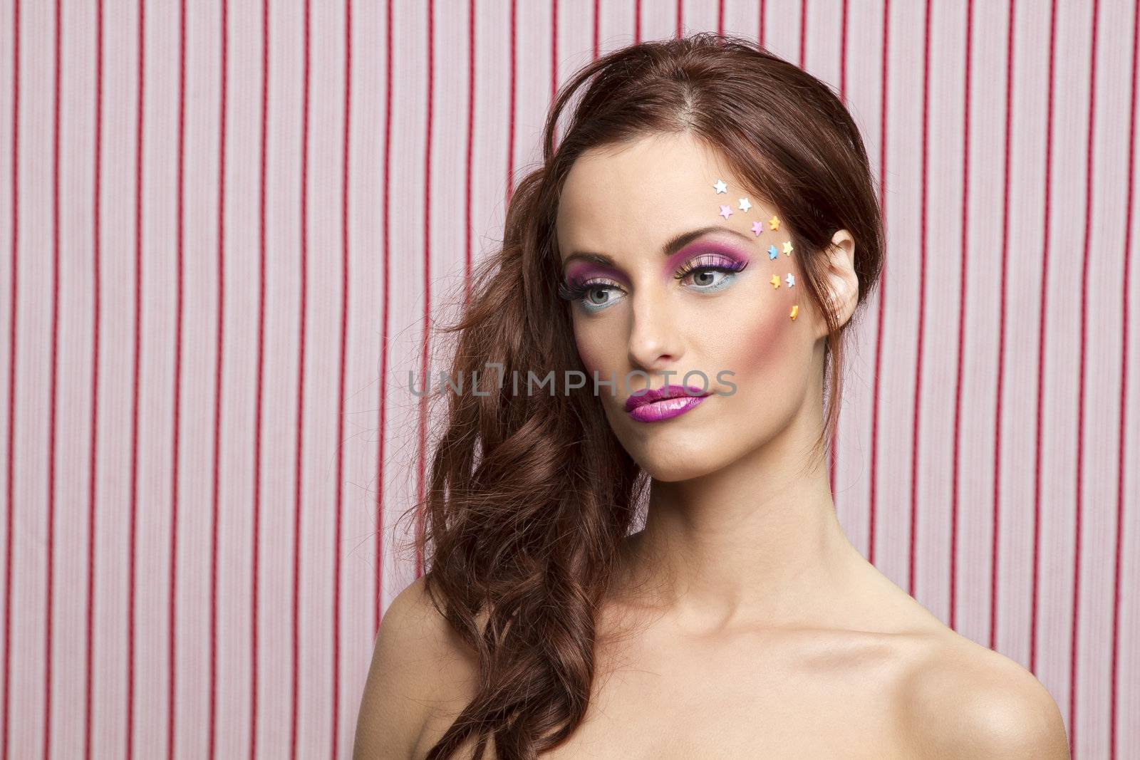 Young woman with colorful makeup and star candy glued to her face
