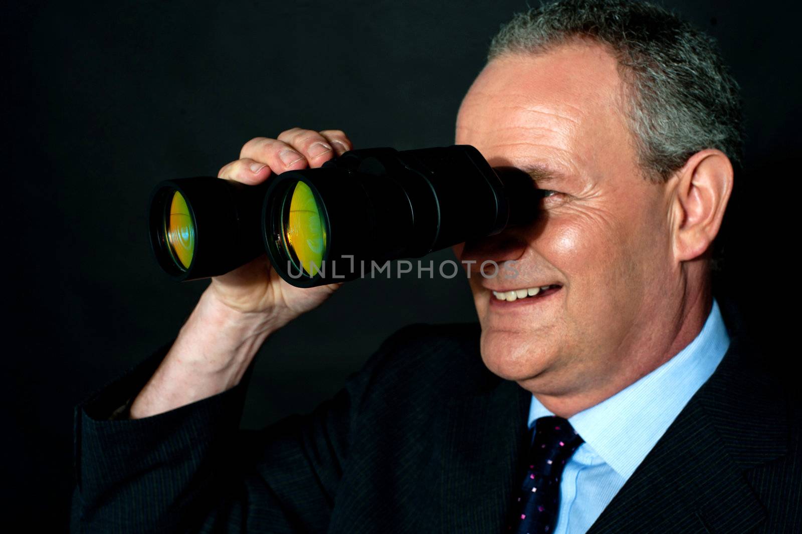 Aged executive monitoring through binoculars isolated over black background