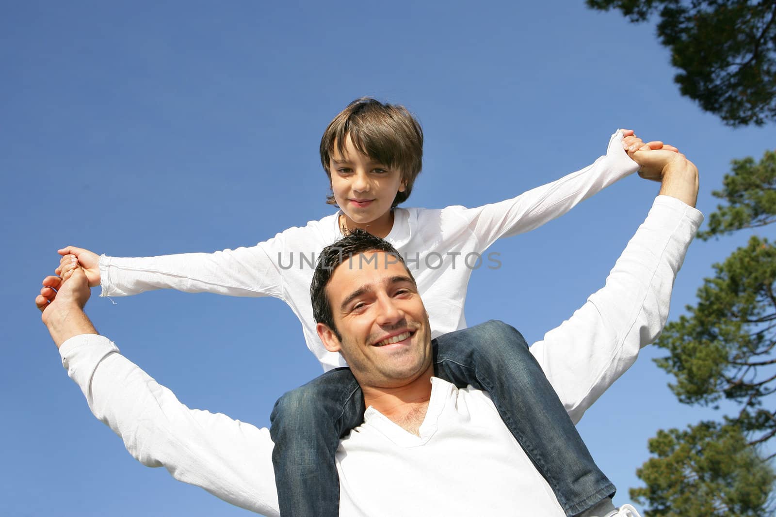 Little boy riding on his father's shoulders by phovoir