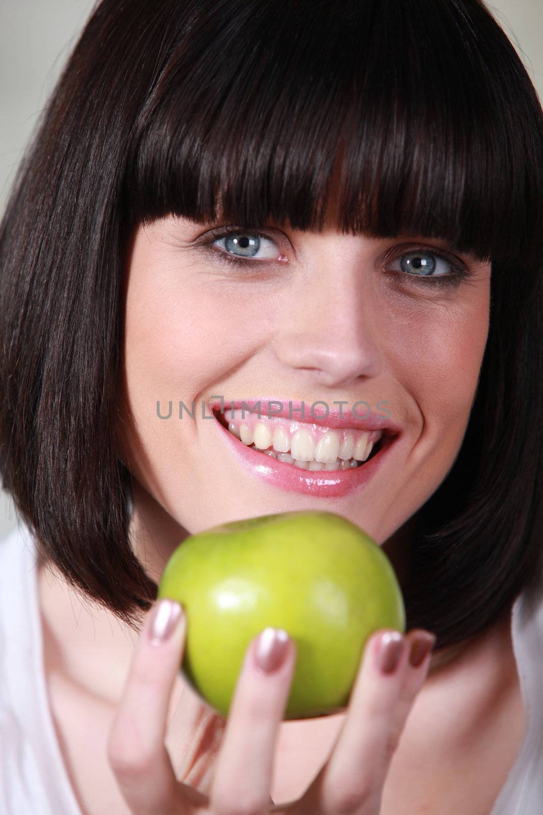 Woman with a big smile and a green apple by phovoir