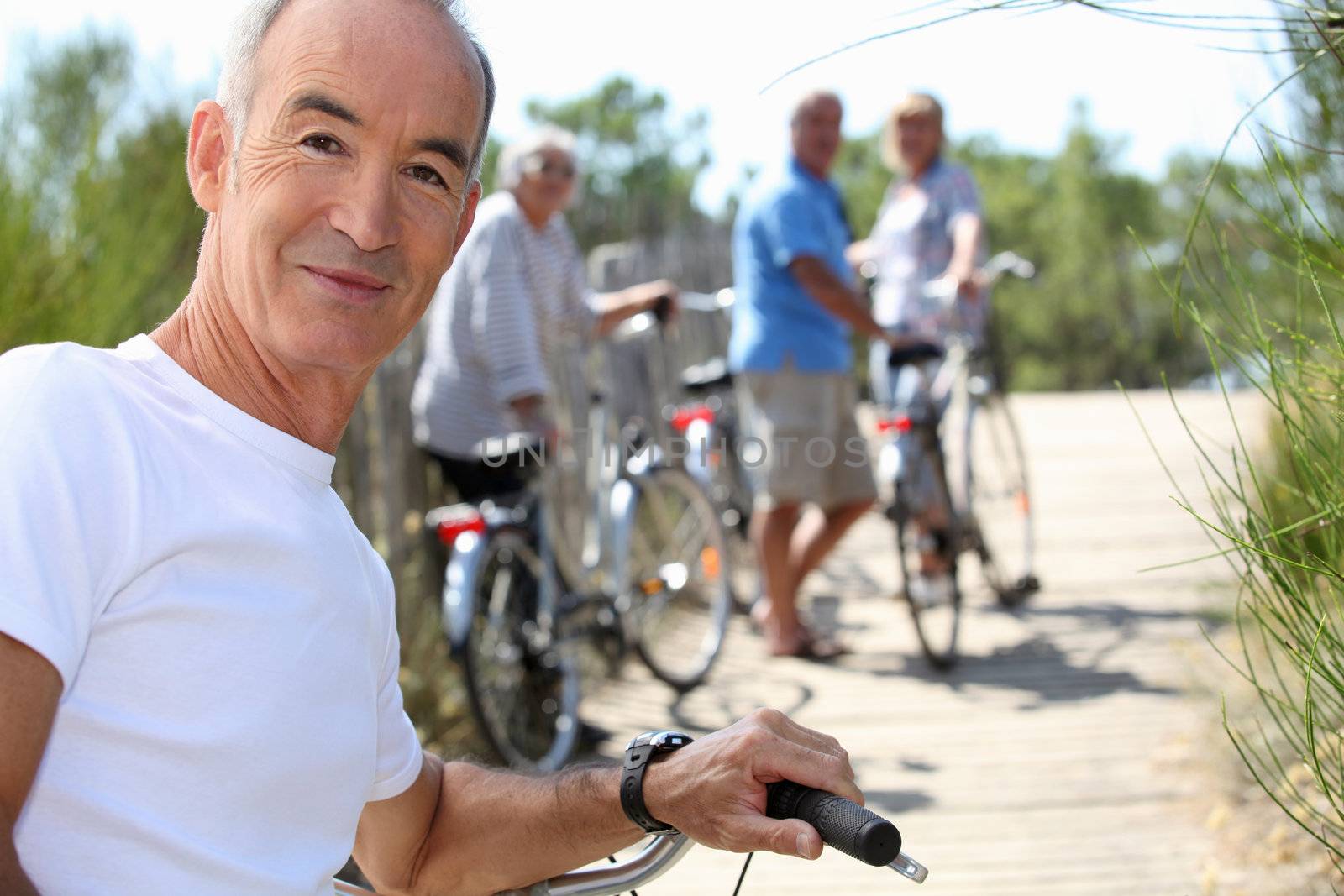 a senior man doing bike with friends in summer