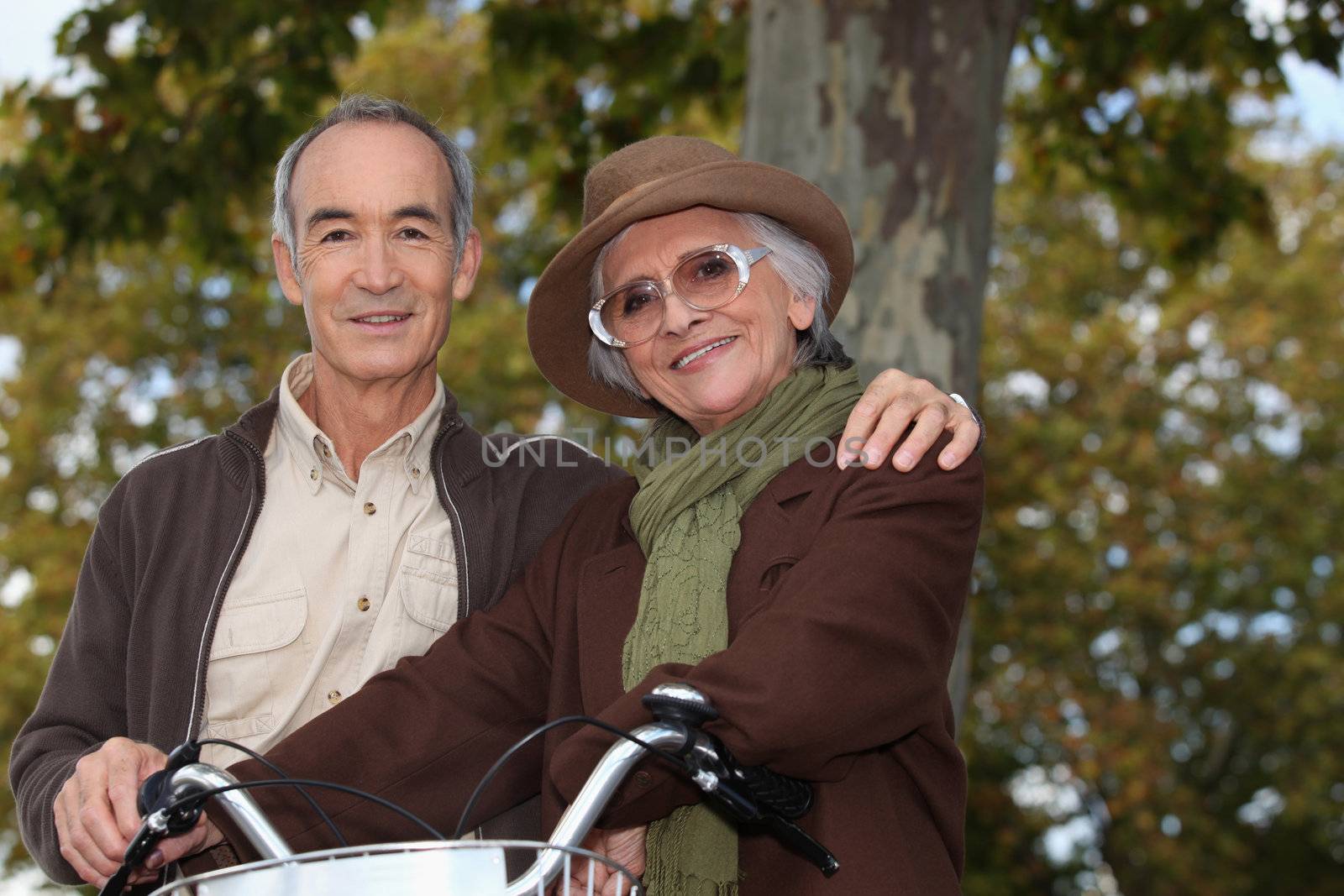 Elderly couple on a bike ride in the forest by phovoir