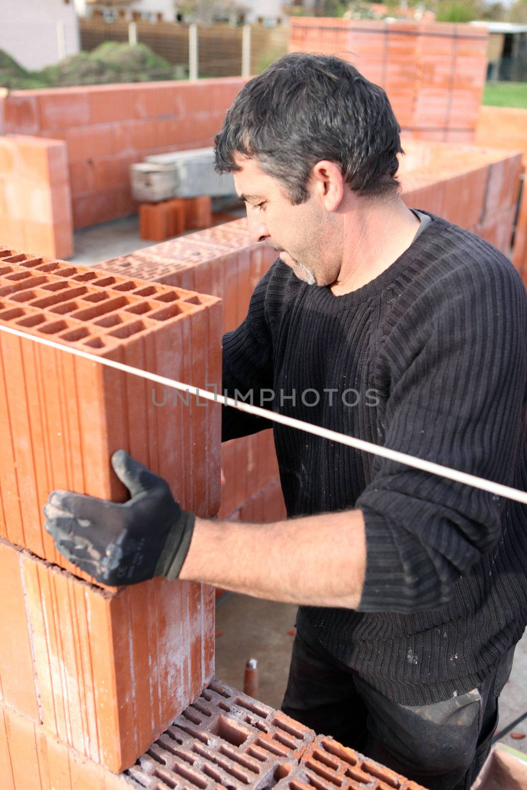 Bricklayer building wall by phovoir