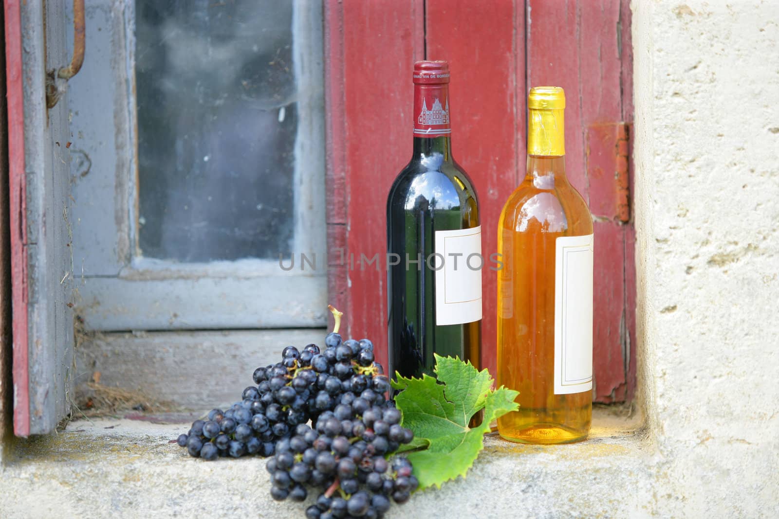 Two bottles of wine on rustic windowsill by phovoir
