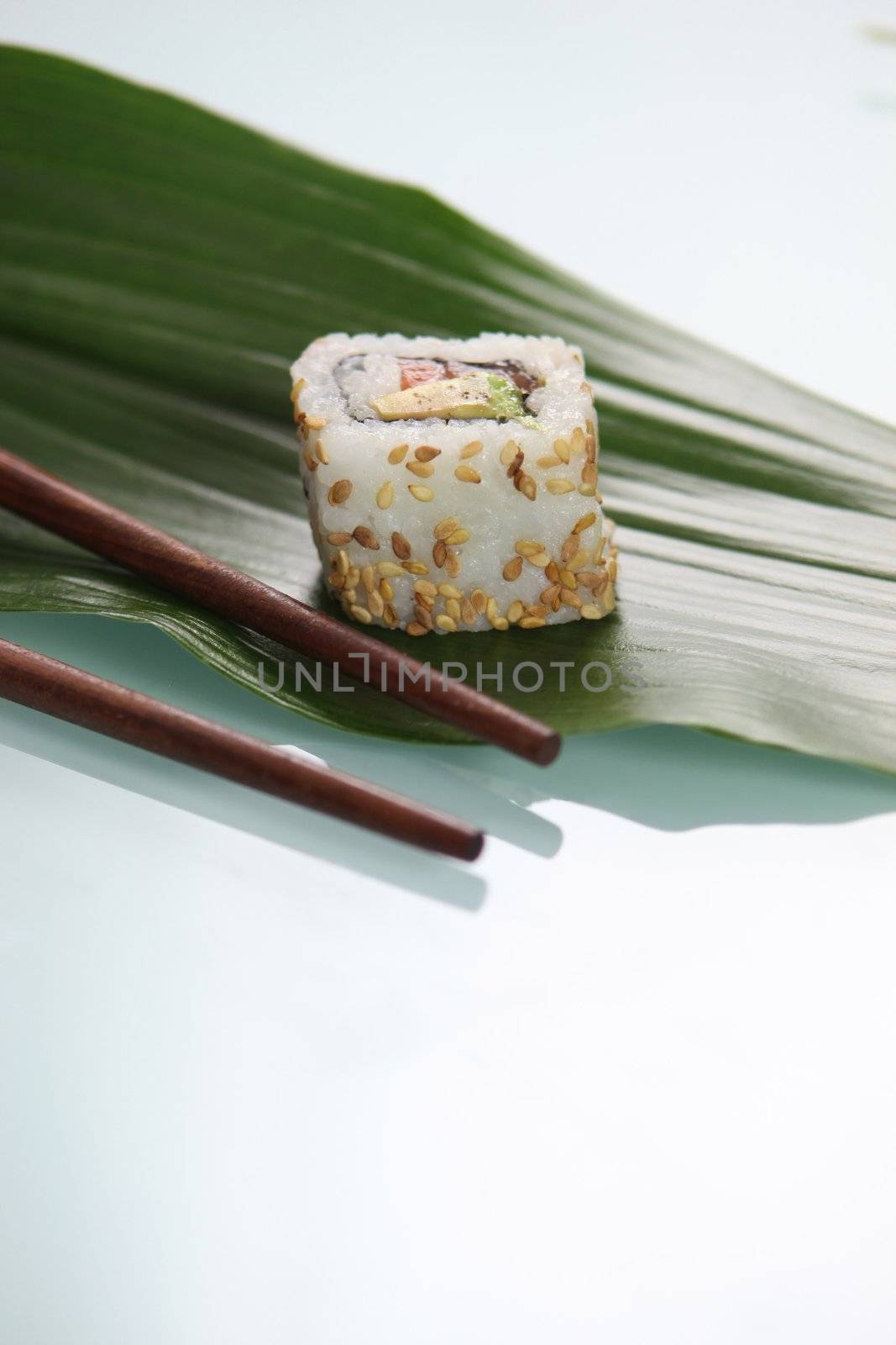 Single sushi resting on green leaf by phovoir