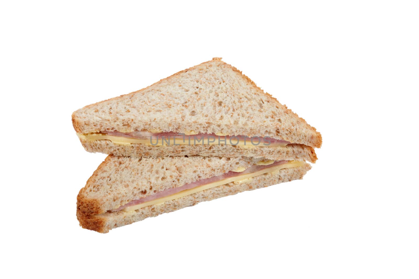 Two halves of a ham sandwich on brown bread
