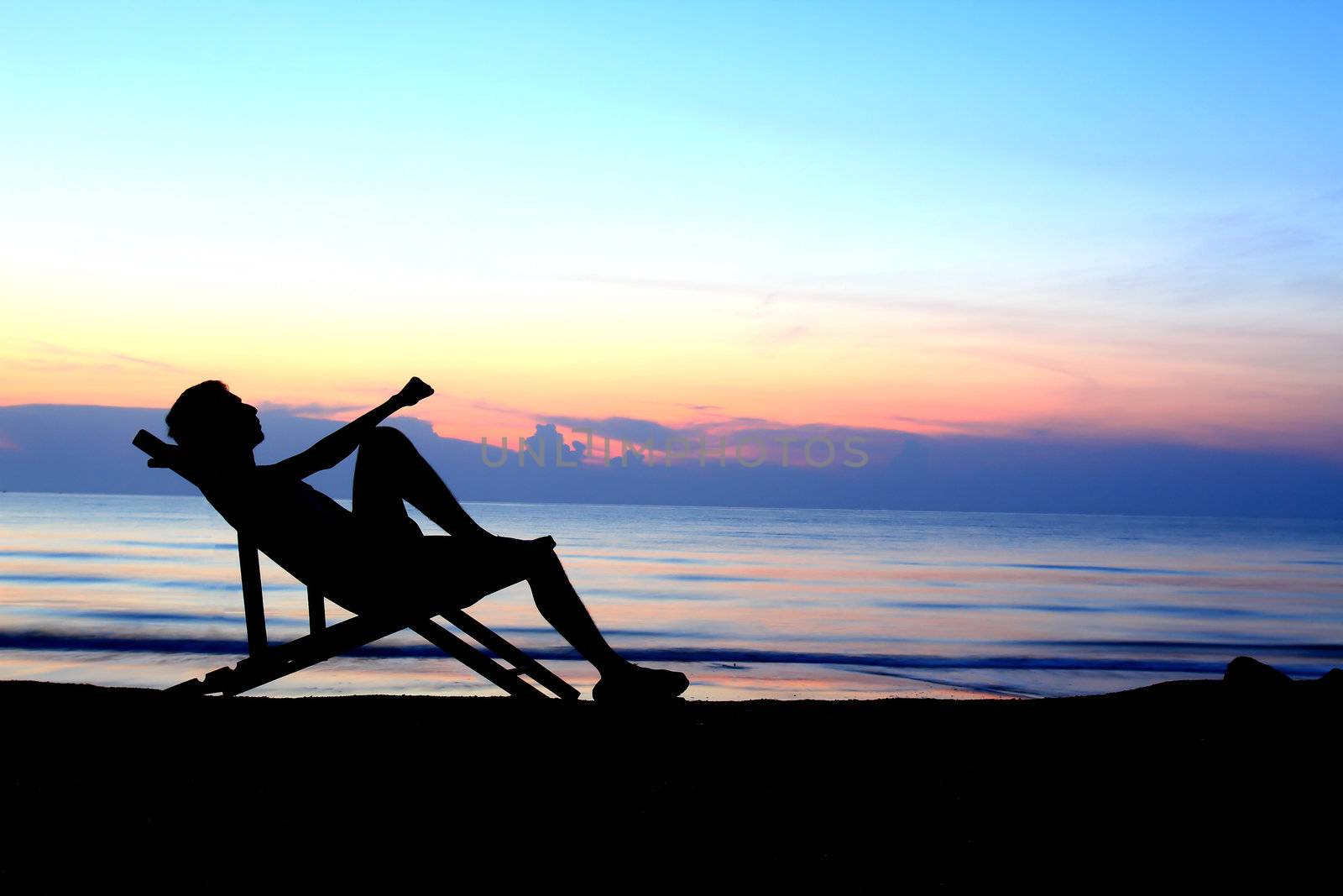 deckchairs and man on beach at sunset