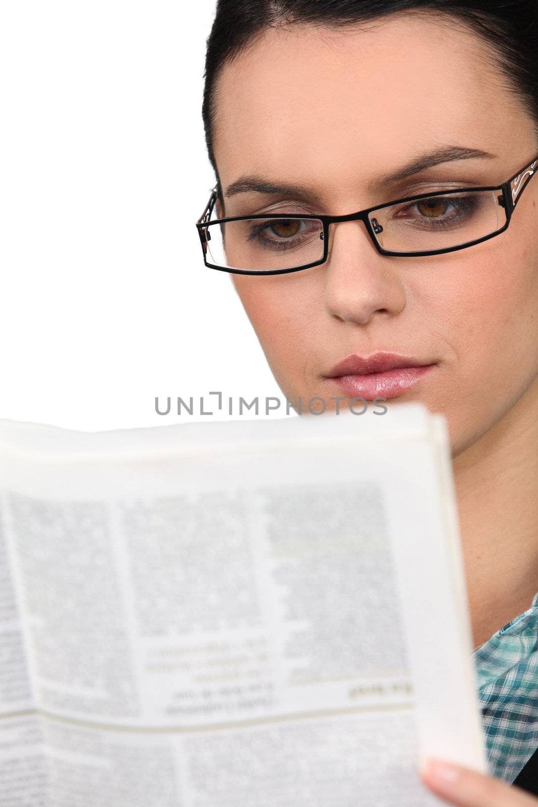 Young woman in glasses reading a newspaper by phovoir