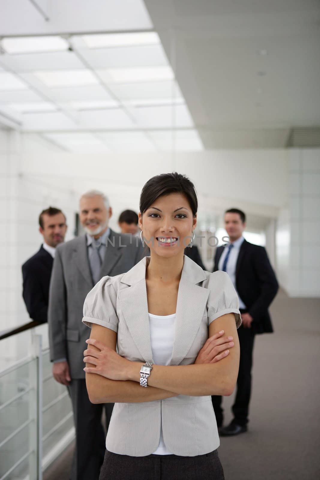 smiling businesswoman standing cross-armed in workplace