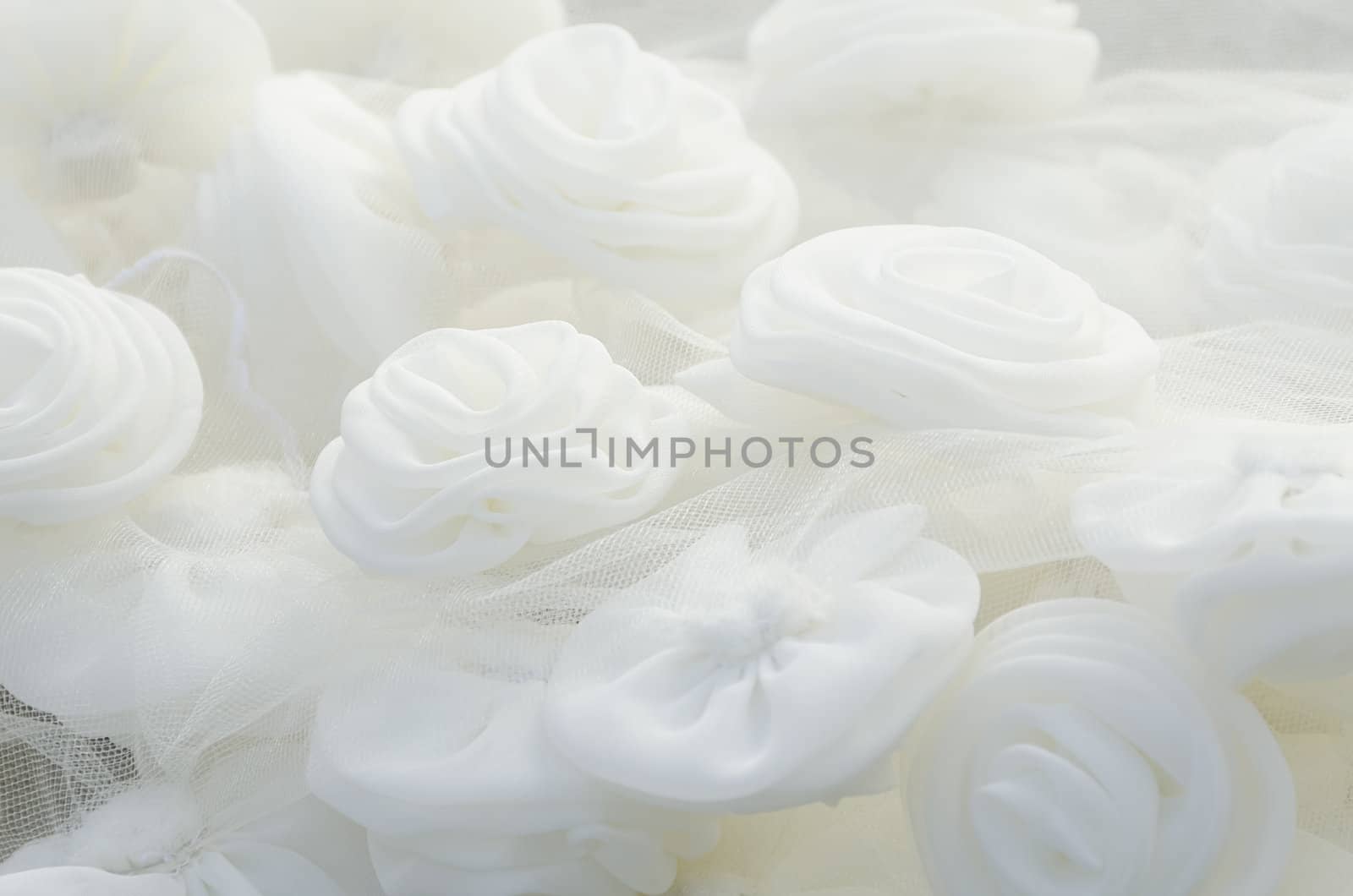 Close-up of beautiful and glowing cloth white roses on wedding gown