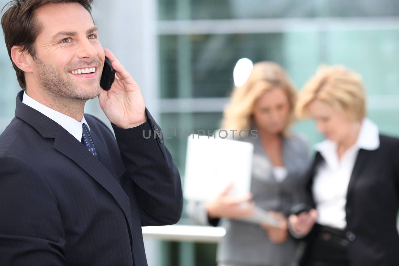 Man speaking in front of two women by phovoir