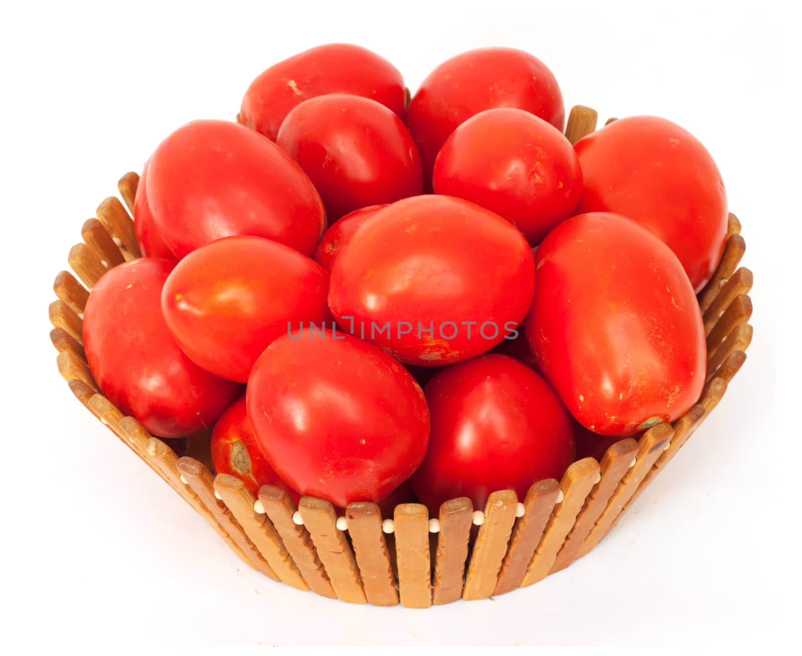 fresh tomatoes on green branch in wicker basket isolated on white background 