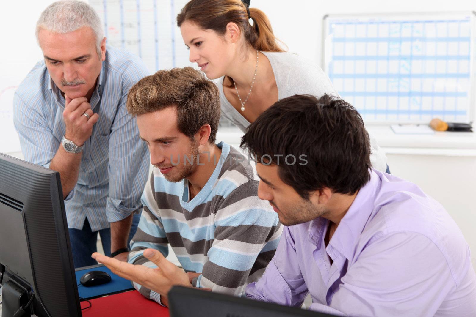 Group of people sitting round a computer by phovoir