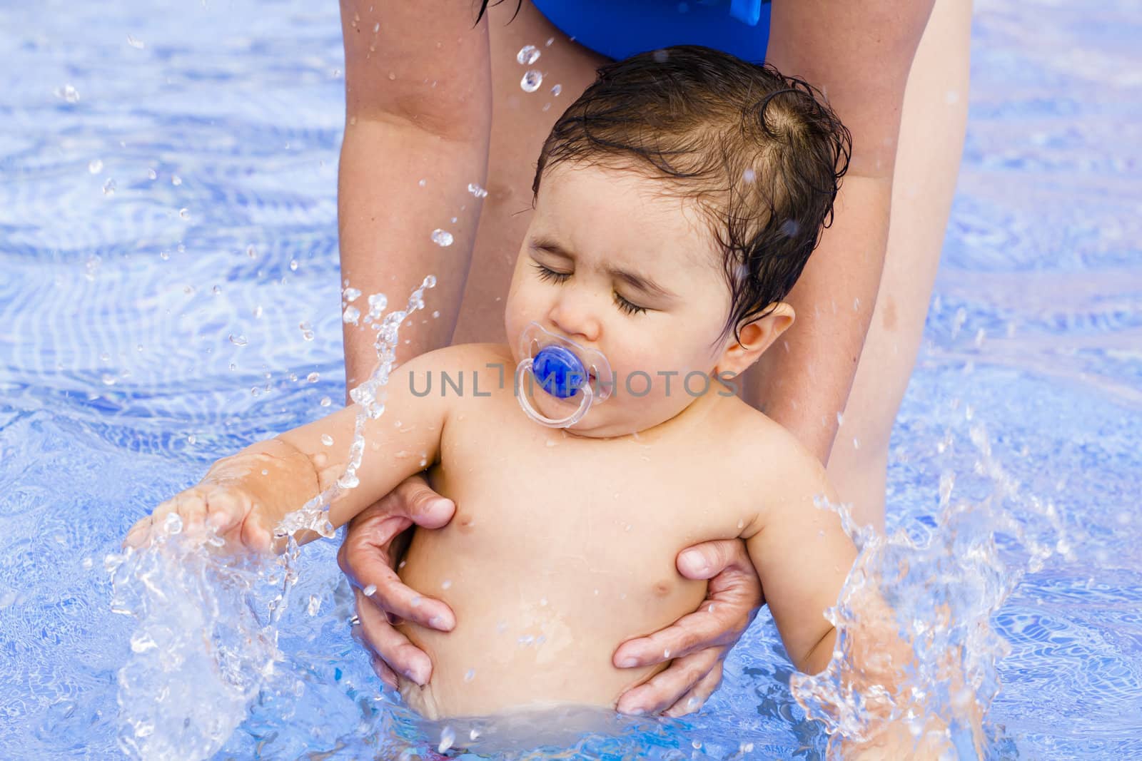 Newborn baby boy playing in the pool with his mother
