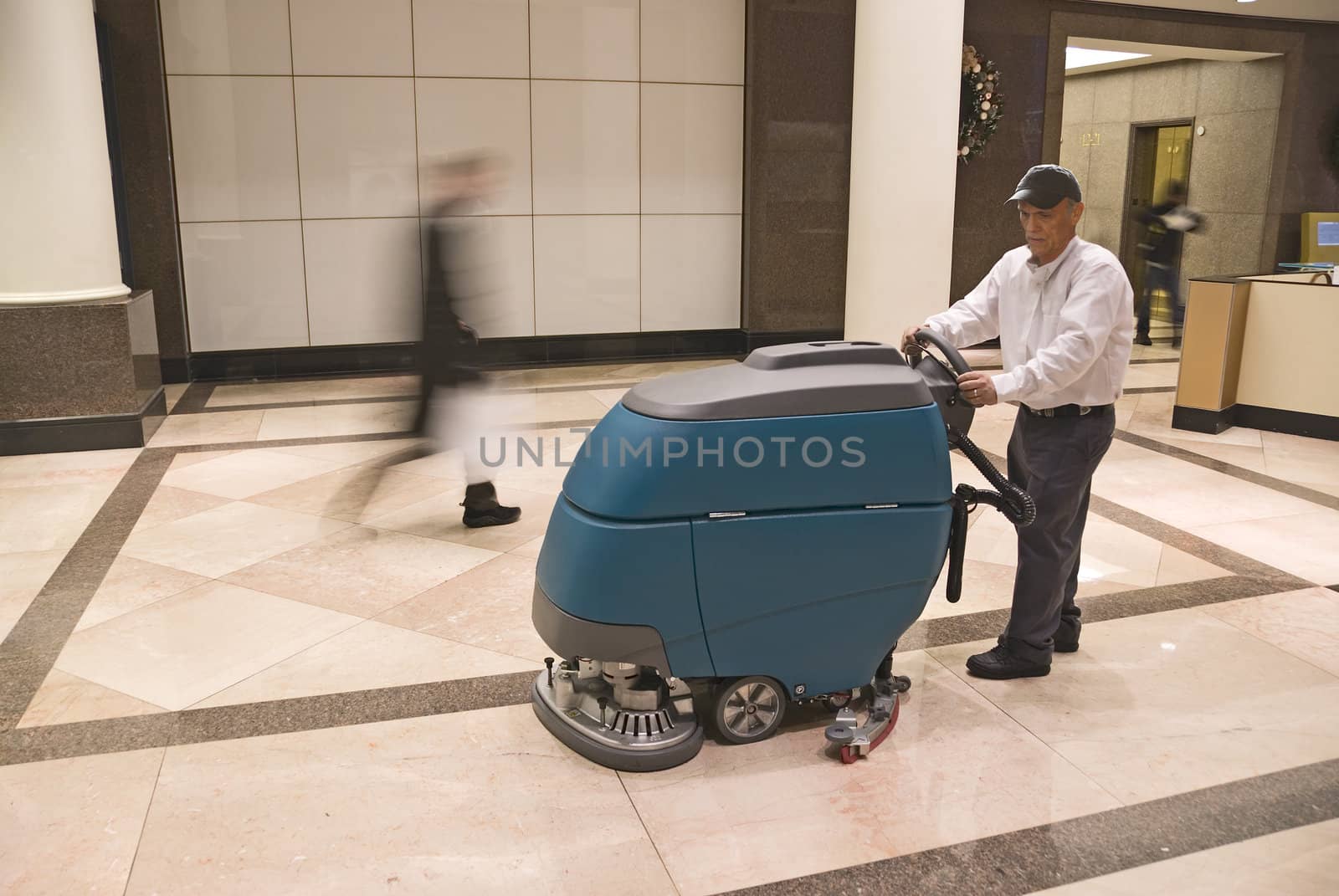 Floor cleaning machine operator in commercial building lobby