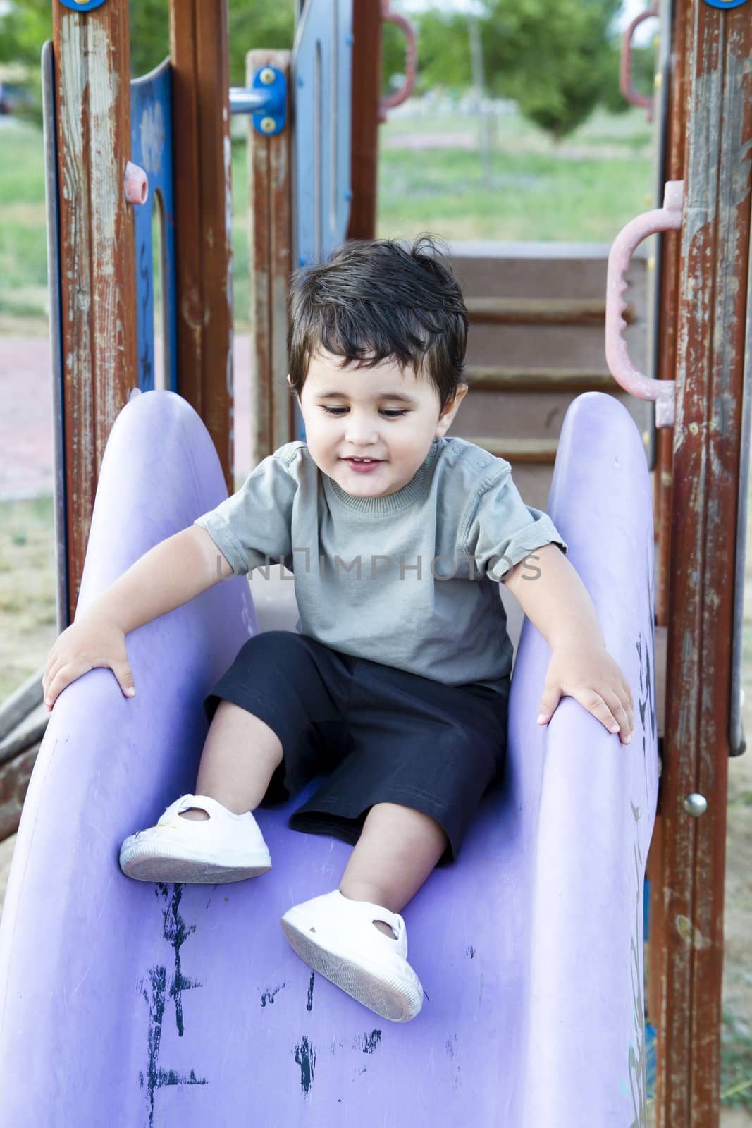 Cute baby playing on sliding board, smiling by FernandoCortes