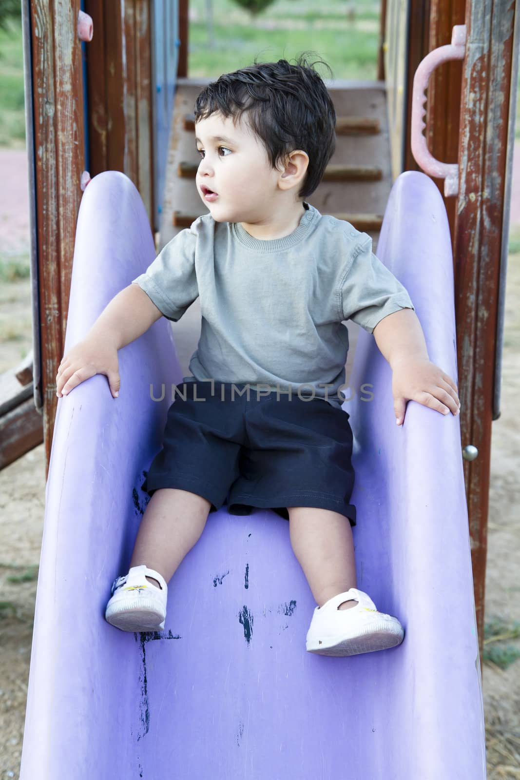 Caucasian baby boy playing on sliding board by FernandoCortes