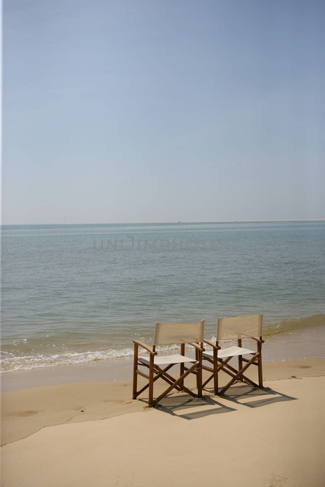 Two empty chairs on a beach by phovoir