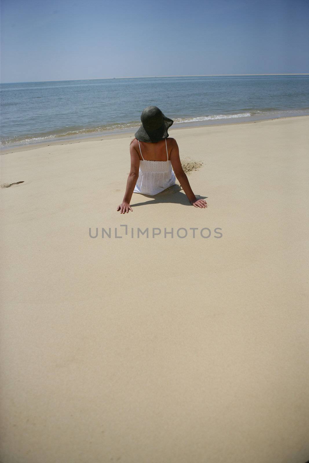 Woman sitting on a beach by phovoir