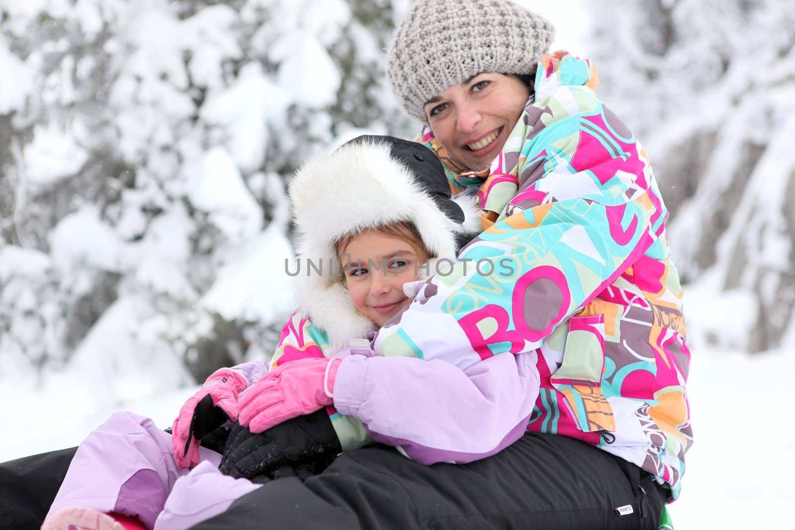 Mother and daughter playing in the snow together by phovoir