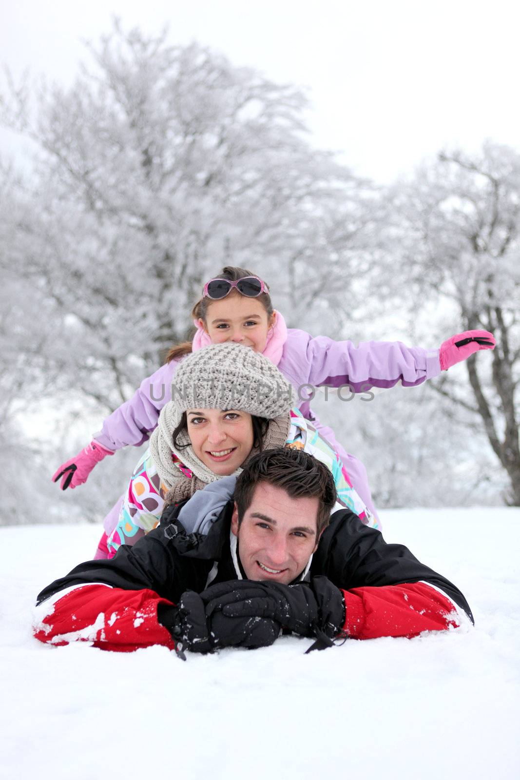 Family laying down in the snow by phovoir