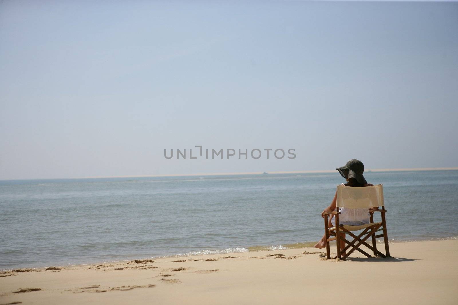 Woman sitting on the beach by phovoir