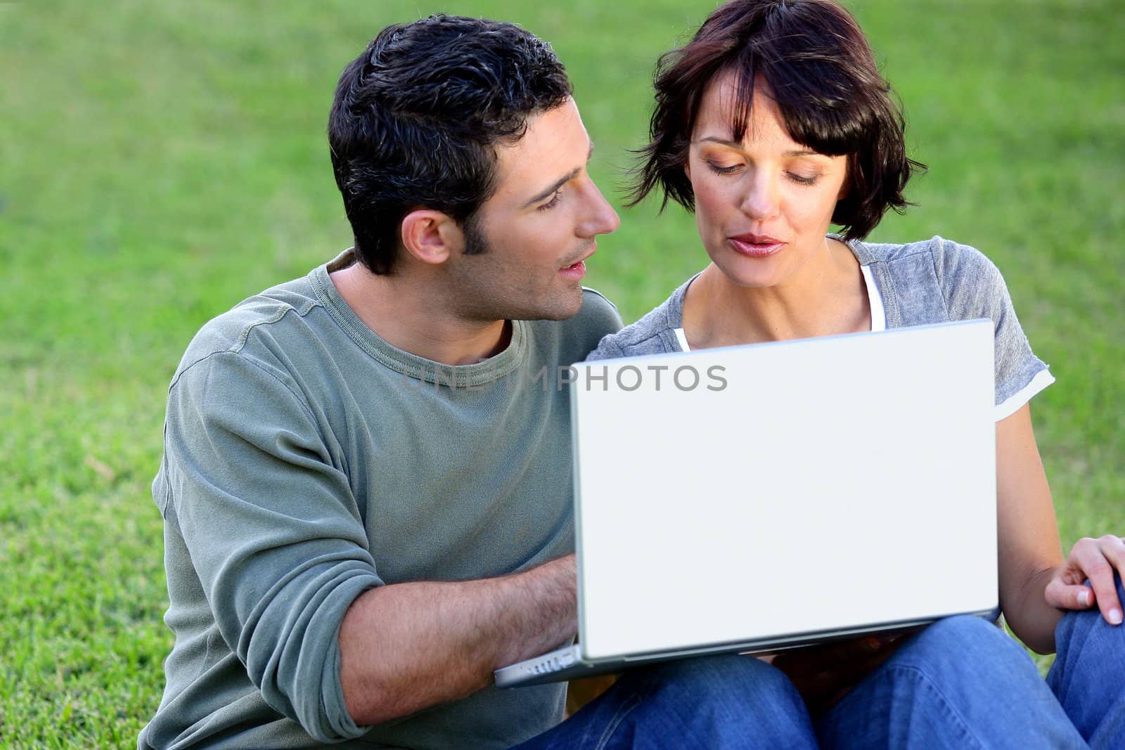Couple making use of free wifi in the park by phovoir