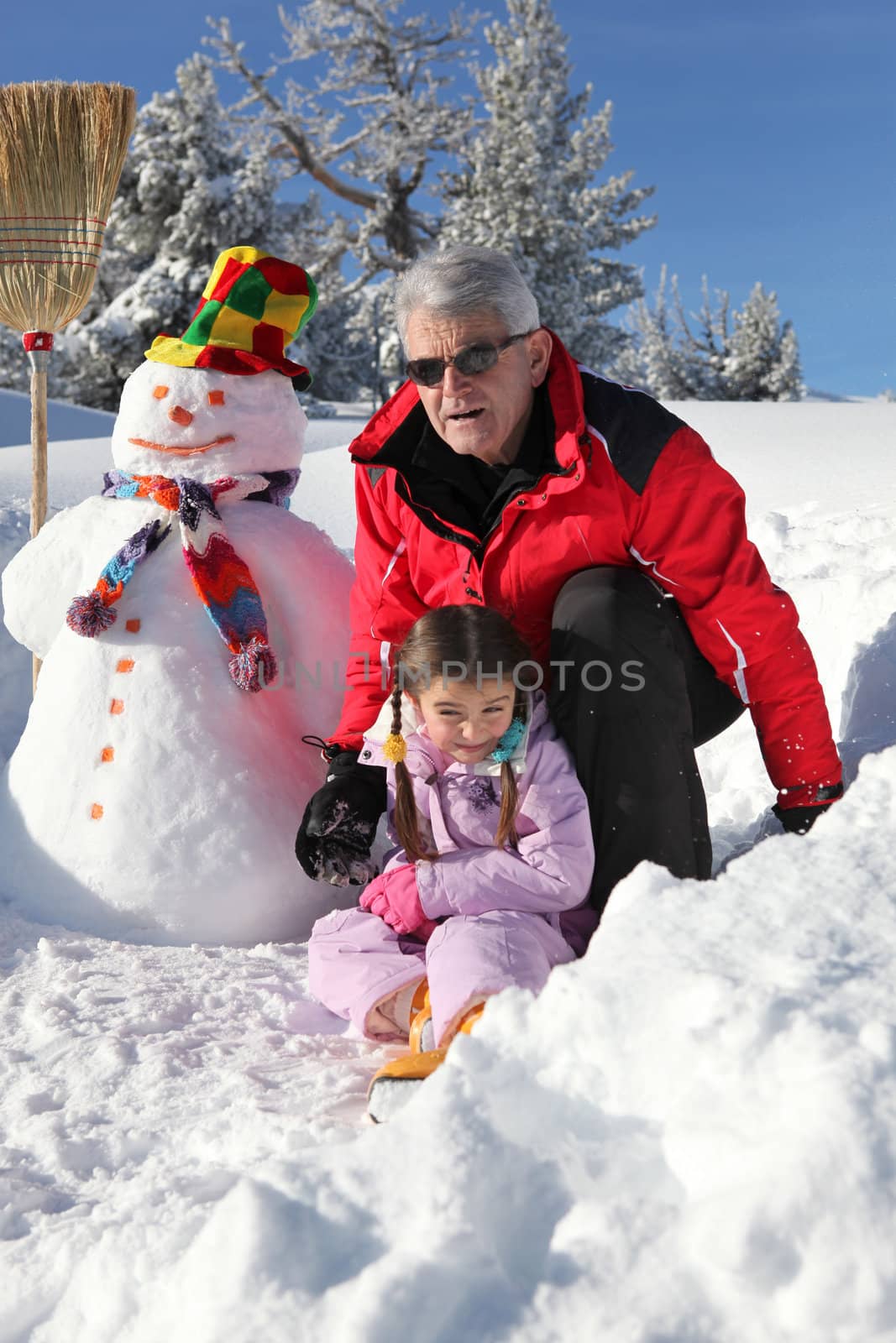 Man and his granddaughter with a snowman by phovoir