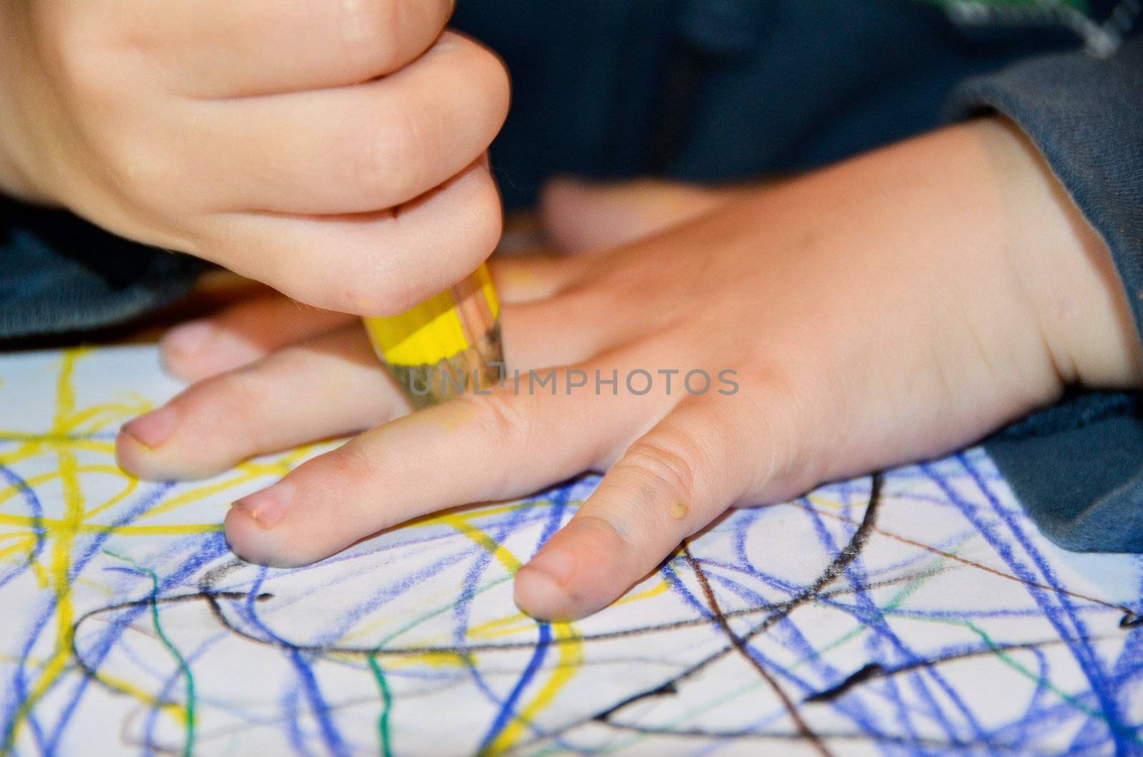 Closeup of a child drawing around its hand with a yellow pen on paper