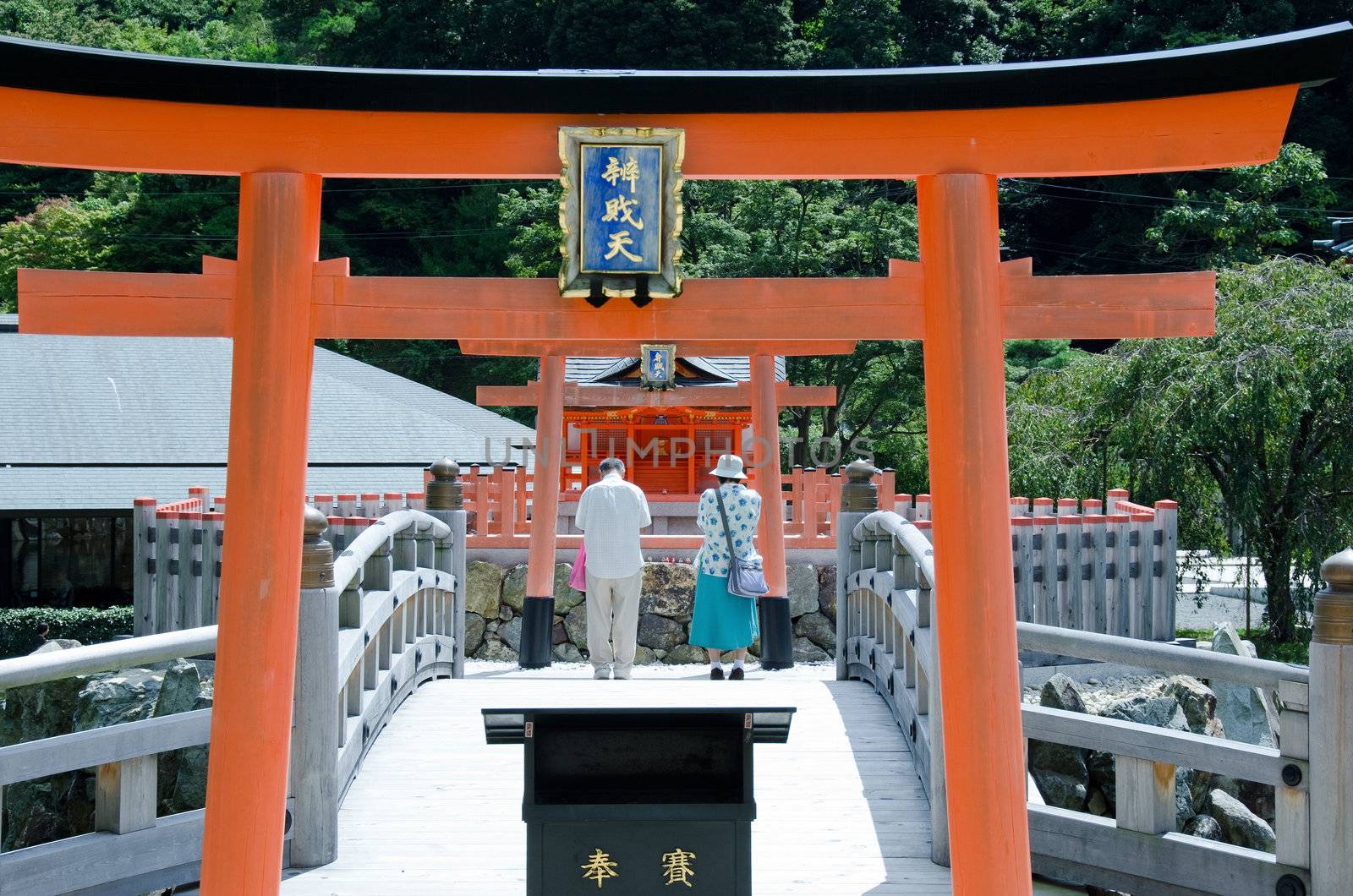 Two people praying at a buddhist shrine in Japan 