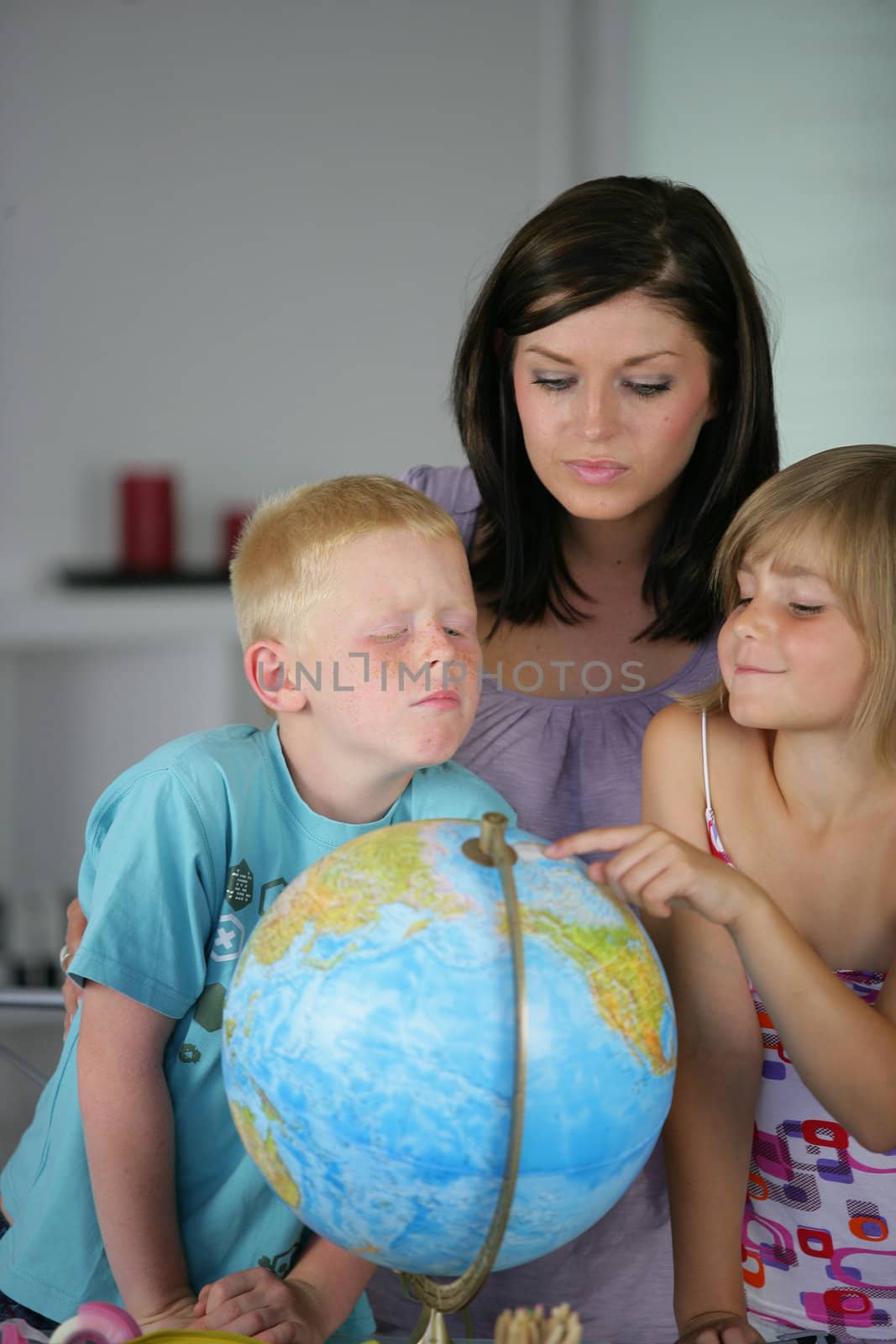 Woman and children looking at a globe by phovoir