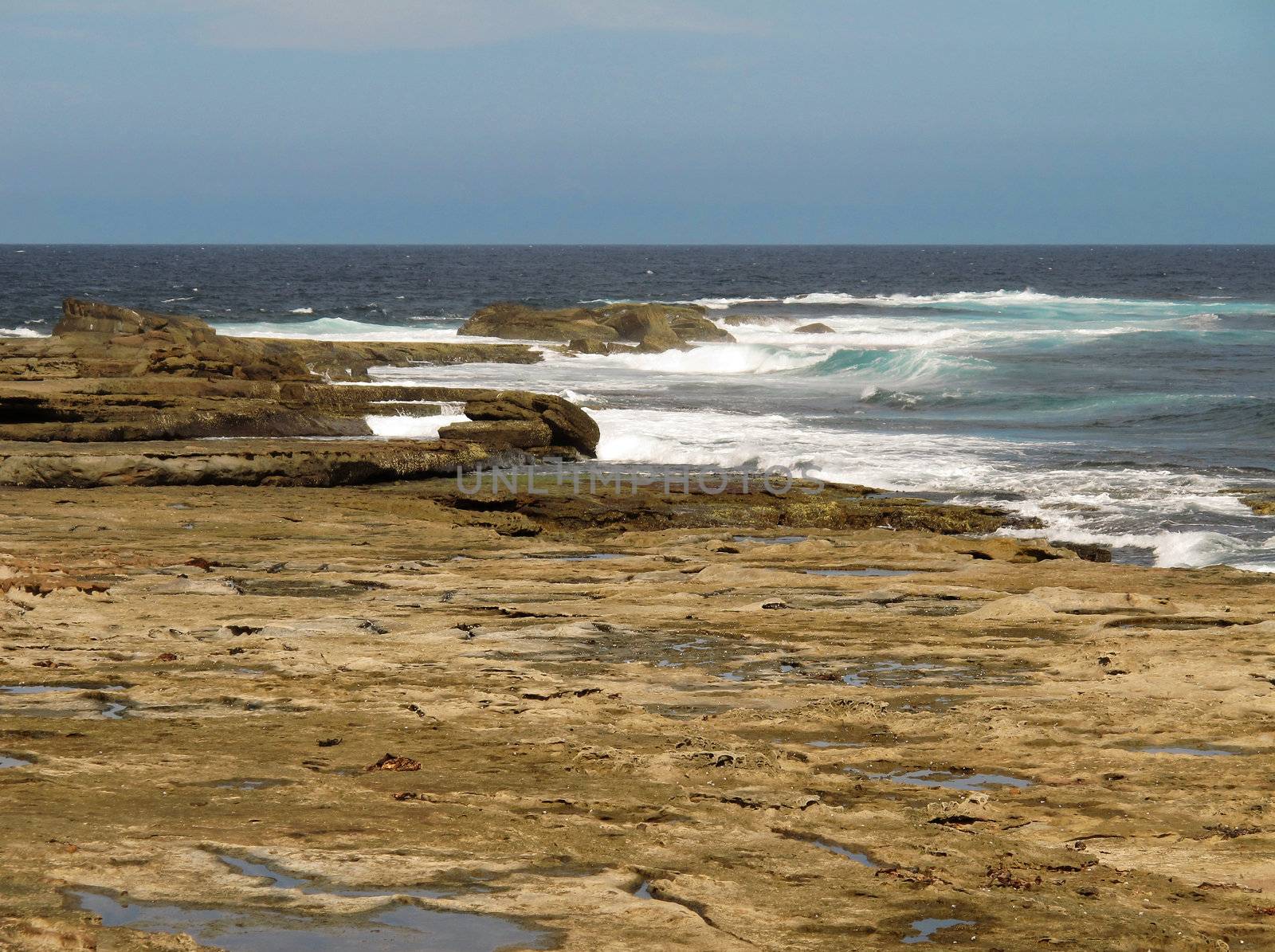 Tidal rock platform in australia with ocean in the background and neutral sky