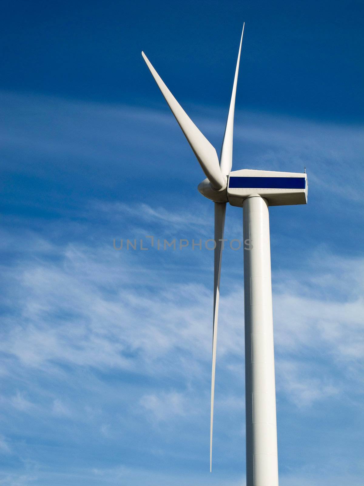 wind turbine seen from the side against blue sky with light clouds