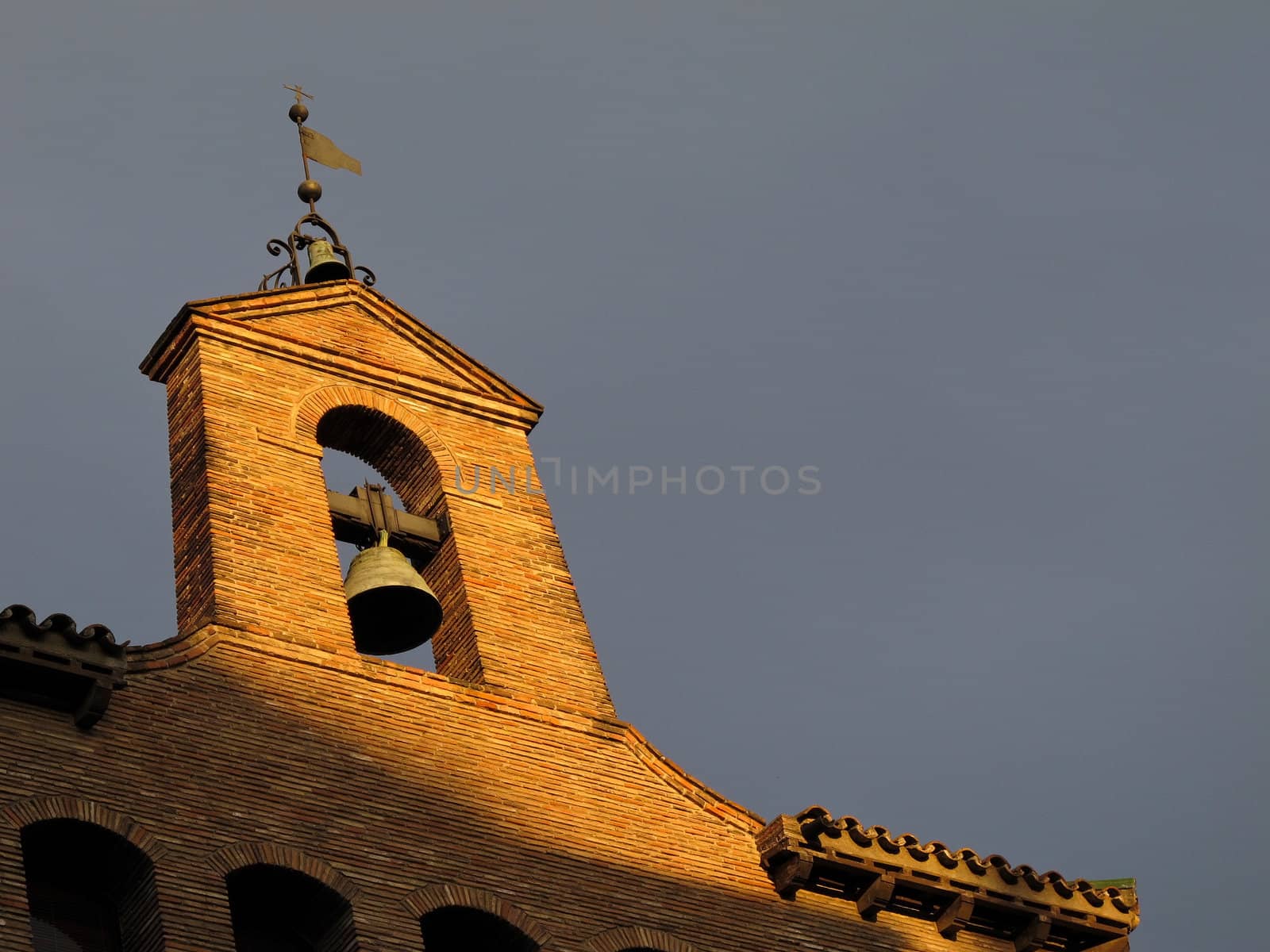 church bell on open belfry tower in warm sunlight