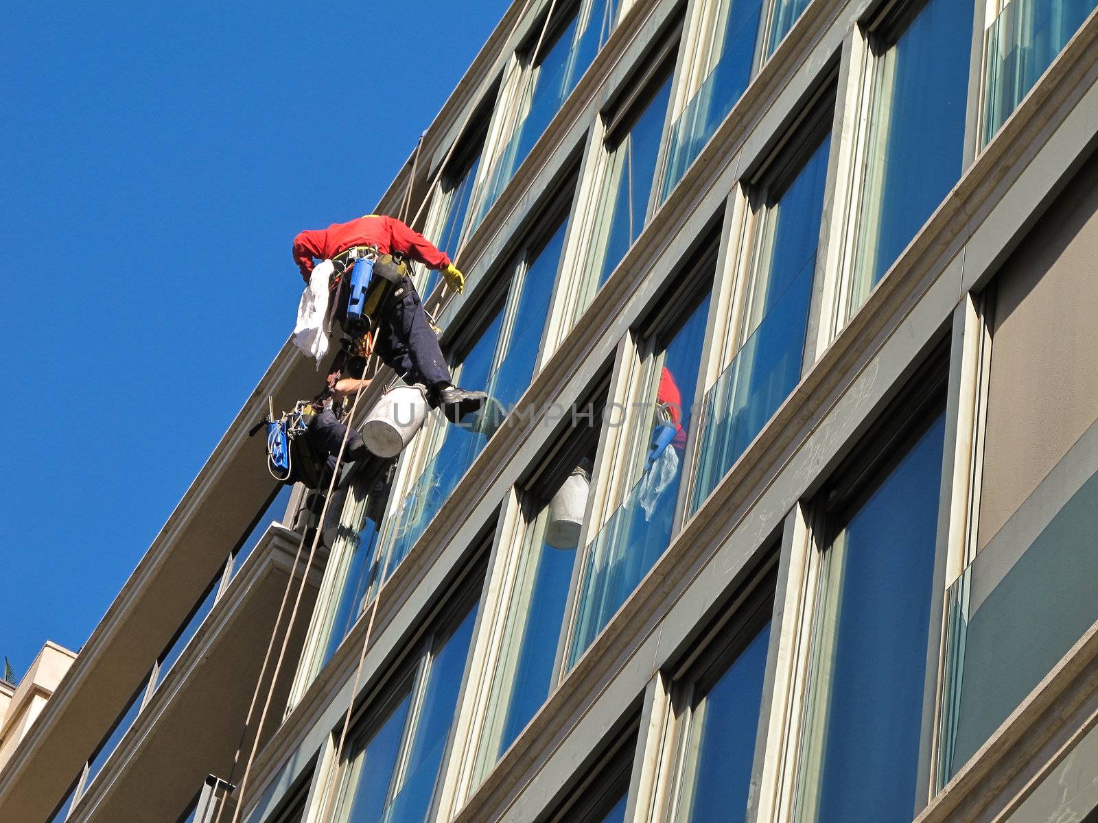 Two workers cleaning windows of a office building using climbing equipment