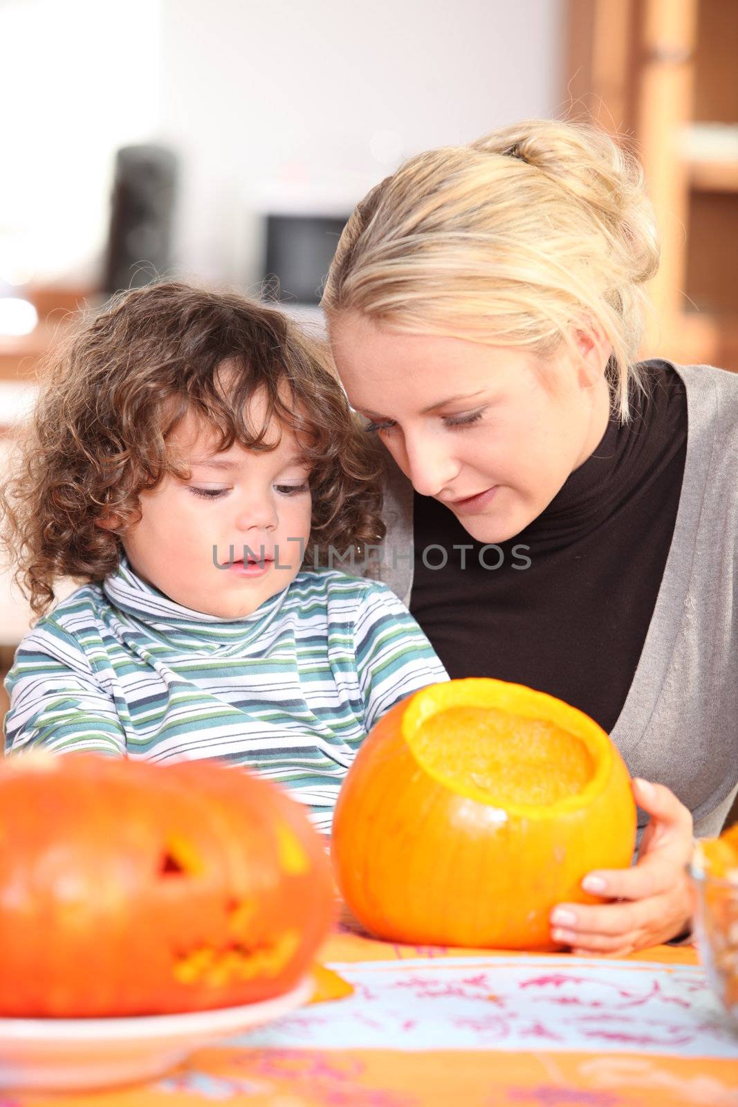 Mother and son carving pumpkin by phovoir