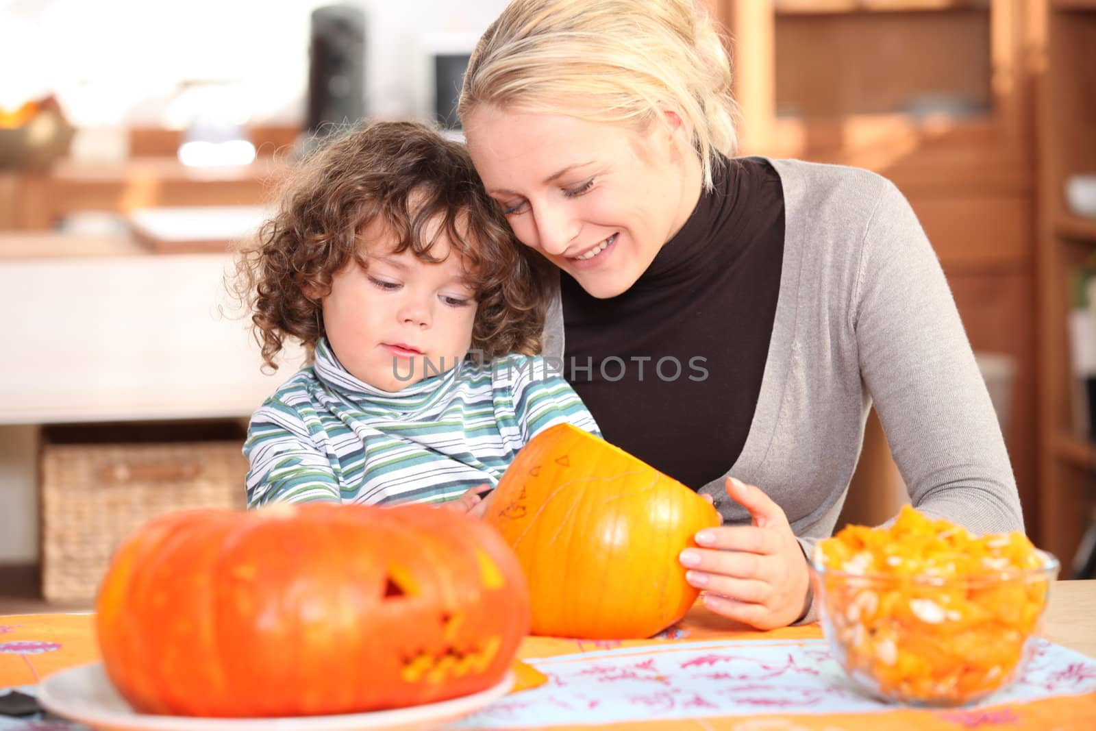 Mother with child decorating pumpkin by phovoir