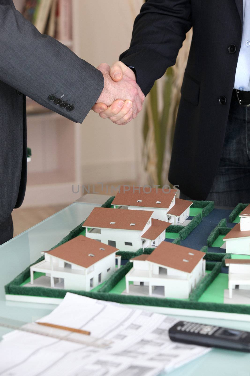 Handshake over a model housing estate by phovoir