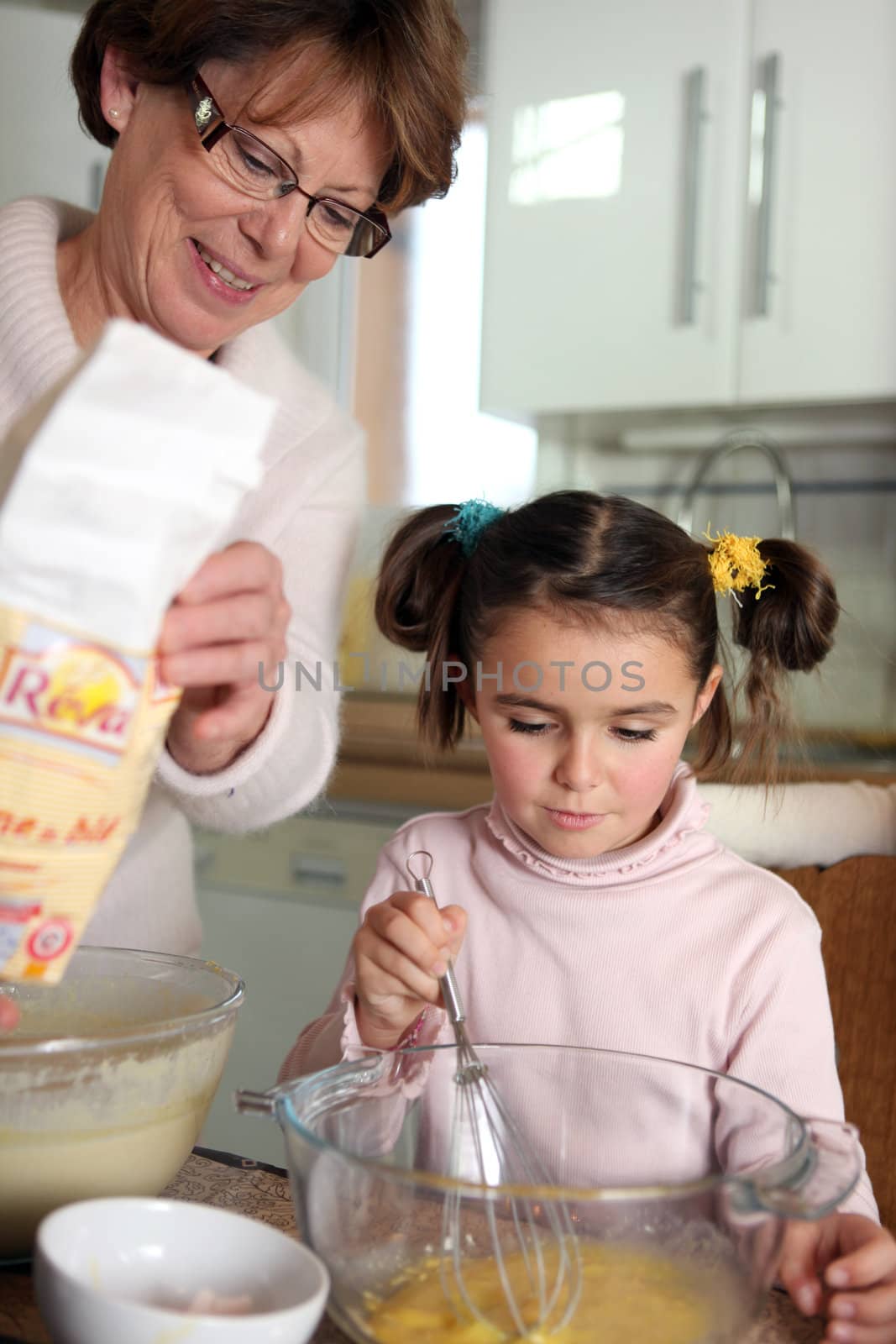 Mother and daughter baking in the kitchen by phovoir