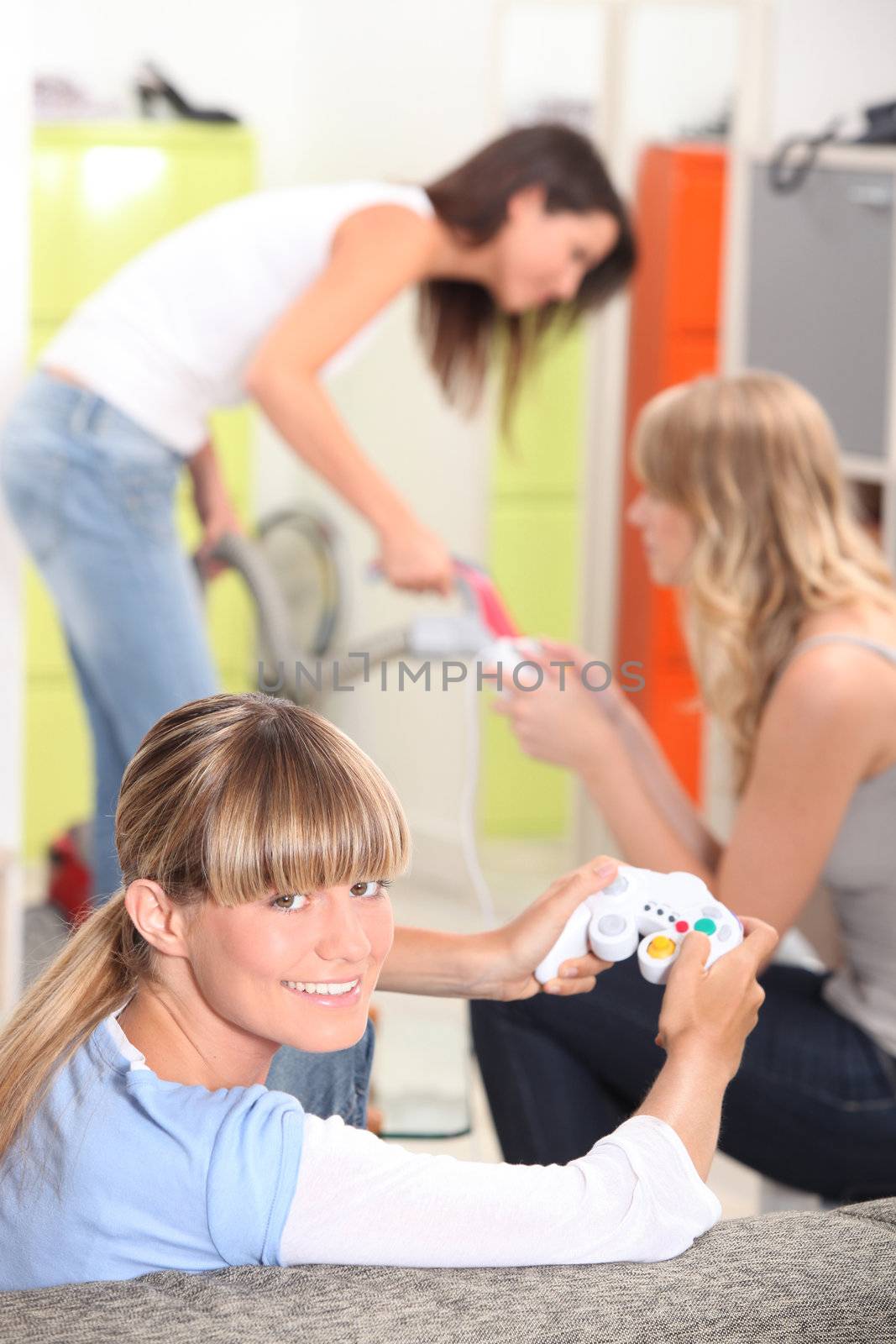 Three female roommates playing video game. by phovoir