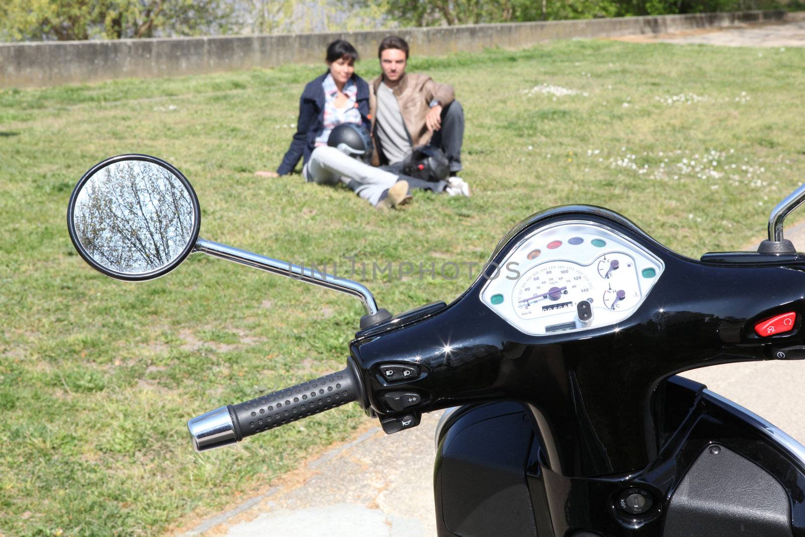 Motorcycle parked on the grass and couple by phovoir